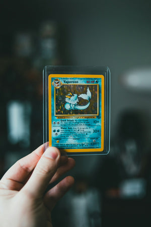 Carte holographique glissée dans un toploader, tenue à la main